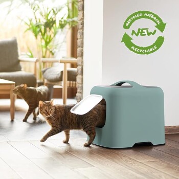 Eine getigerte Katze verlässt eine moderne, mintgrüne Katzentoilette mit einer weißen Klappe, beschriftet mit "NEU" und gekennzeichnet als "Recyceltes Material" und "Recycelbar."
