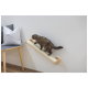 Eine Katze geht auf einem wandmontierten Kratzbaum neben einem Stuhl mit grau-weißen Kissen, vor einer hellen Wand.