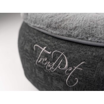 Eine Nahaufnahme eines stilvollen Haustierbettes mit einer weichen grauen Oberseite und einer strukturierten dunkelgrauen Basis, mit dem gestickten Text "TrendPet."