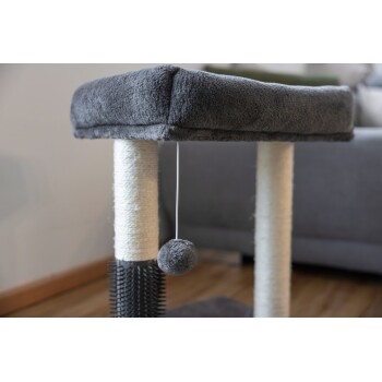 Grauer und beiger Katzenkratzbaum mit hängendem grauem Bommelspielzeug auf Holzboden neben grauem Sofa.