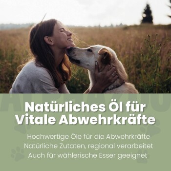 Frau hält einen Hund und berührt mit der Nase die des Hundes auf einem Feld mit dem Text „Natürliches Öl für Vitale Abwehrkräfte“ zur Förderung der Immunabwehr.