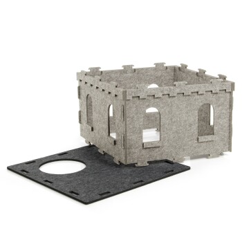 Eine graue Filzhaustierburg mit Wänden und Fenstern, teilweise zusammengebaut, neben einer schwarzen Basis mit einer runden Öffnung.