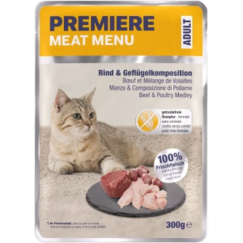 Eine hellbraune Katze sitzt neben einem Schieferplatte mit rohem Fleisch, mit einem Verpackungslabel, das 'Premiere Meat Menu' und 'Rind & Geflügel Medley' liest.