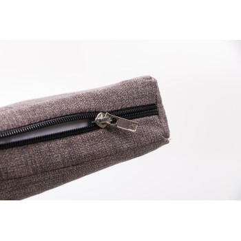 Nahaufnahme einer grauen Haustieraccessoire-Tasche mit einem schwarzen Reißverschluss, die den Reißverschluss und den strukturierten Stoff zeigt.