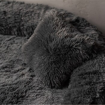 Weiches, plüschiges graues Haustierbett mit passendem Kissen, mit einer zotteligen Textur für Komfort.