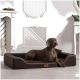 Ein grauer Hund, der auf einem stilvollen braunen Haustierbett in einem hellen, eleganten Raum mit weißen Wänden und dekorativen Akzenten entspannt.