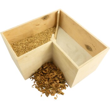 Eine Holzkiste, die in zwei Abschnitte unterteilt ist, einer gefüllt mit Holzspänen und der andere mit Sand, mit einem Haufen Holzspäne daneben.