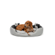 Ein brauner Hund, der auf einem runden, plüschigen Hundebett mit grauem und schwarzem Farbschema ruht, mit einem weichen, gepolsterten Design.