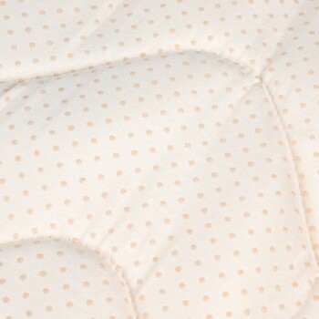 Close-up of a beige pet bed with light brown polka dots and cushioned, quilted fabric.