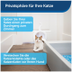 Eine Katze auf einem Holzboden neben einer Katzentoilette, mit deutschem Text, der die Privatsphäre der Katze und das Verstecken von Katzentoiletten oder Futter vor Hunden fördert.
