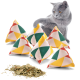 Eine graue Katze interagiert verspielt mit bunten dreieckigen Katzenminze-Kissen, mit getrockneter Katzenminze, die auf der weißen Oberfläche verstreut ist.