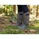 Ein Paar graue Gummistiefel mit Blumenmustern, getragen von einer Person, die auf moosigem Boden in einem Wald steht.