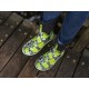 Ein Paar lebhaft grüne und schwarz gemusterte Gummistiefel, die von einer Person auf einer Holzterrasse getragen werden.