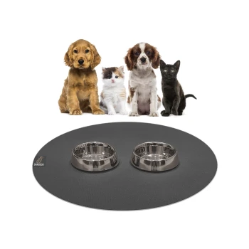 Ein verspielter Welpe, ein flauschiges Kätzchen und eine schlanke schwarze Katze sitzen vor einer runden Tiermatte mit zwei Edelstahlschüsseln darauf.