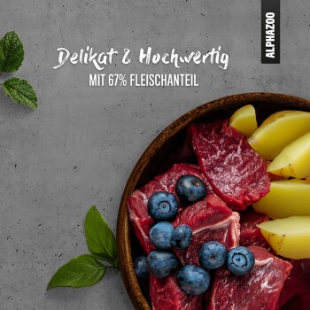 Schüssel mit rohen Fleischstücken, Heidelbeeren und Kartoffelscheiben, mit dem Text "Delikat & Hochwertig mit 67% Fleischanteil" darüber.