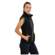 Eine Frau trägt eine schwarze ärmellose Steppweste über einem grünen Shirt und steht mit den Händen in den Taschen der Weste.