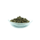 Eine Glasschüssel gefüllt mit dunkelbraunen Haustierfutterpellets, die in einem Hügel vor einem weißen Hintergrund angeordnet sind.
