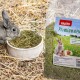 Ein grauer Hase, der Heu aus einer weißen Schüssel frisst, neben einem Sack mit der Aufschrift "PANTO Premiumheu", der Bilder von Hasen und Meerschweinchen zeigt.
