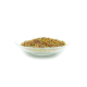 Bunte Haustierfutterpellets in einer klaren Glasschüssel, mit roten, grünen und gelben Farbtönen, vor einem weißen Hintergrund.