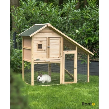 Ein Holzkaninchenstall mit einem schrägen Dach, mit einer kleinen Tür und einem Drahtgeflecht, steht auf grünem Gras. Ein weißes Kaninchen ist darin.