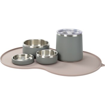 Ein Set aus Fressnäpfen für Haustiere und einem Wasserglas in gedämpftem Grau mit Edelstahl-Innenflächen, auf einer hellrosa Silikonmatte platziert.