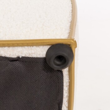 Nahaufnahme eines Haustierbettes mit einer weichen, weißen Textur, einem goldenen Metallrahmen und einer schwarzen Stoffbasis mit einem Gummifuß.