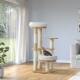 A stylish cat tree with a cozy bed and scratching posts, featuring a playful cat sitting on the lower level, in a bright living room.