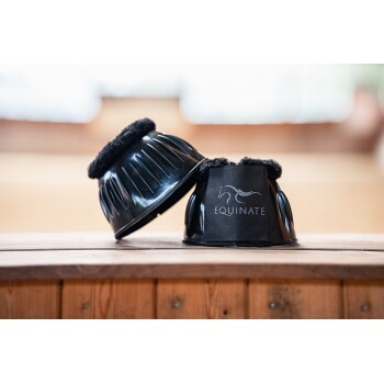 Zwei schwarze Pferdebeinschoner mit weicher Fütterung, einer zeigt das Logo "EQUINATE" und liegt auf einer Holzoberfläche.