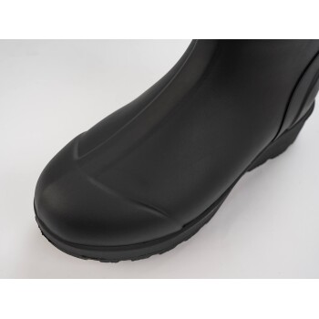 Nahaufnahme eines schwarzen Gummistiefels, der seine glatte Textur und das abgerundete Design auf einem weißen Hintergrund zeigt.