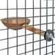 Mangeoire pour oiseaux en coque de noix de coco fixée à un perchoir en bois, sécurisée avec un clip en métal, vue à travers une grille en fil.