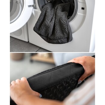 Eine graue Haustierdecke ist teilweise in einer Waschmaschine, während eine Person ein schwarzes Haustierbett mit gestepptem Design hält.