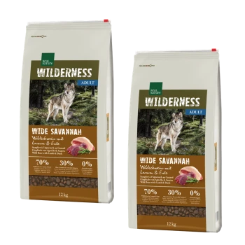 Two bags of dog food labeled "Wilderness Adult Wide Savannah" featuring a wolf and images of meat, with 70% wild boar, 30% lamb & duck, and 0% grains.