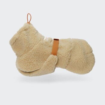 Beiger Sherpa-Hundemantel mit orangefarbenem Riemen und Aufhängeschlaufe, flauschige Fleece-Außenseite vor weißem Hintergrund.