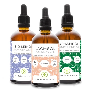 Drei Flaschen Haustieröle: Bio-Leinöl, Lachsöl und Bio-Hanföl, jede mit bunten Etiketten, die Vorteile und Inhaltsstoffe detailliert beschreiben.
