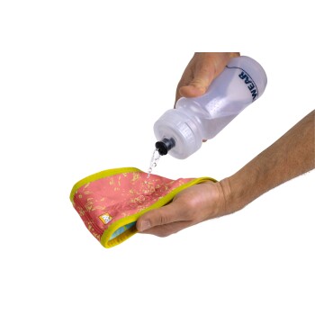 Eine Person gießt Wasser aus einer klaren Flasche auf eine bunte Haustier-Kühlmatte, die ein pinkes und gelbes Design hat.