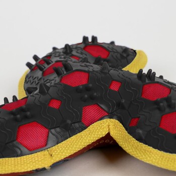 Red and black dog booties with yellow trim and rubber spikes for traction, shown close-up on a white background.