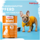 Französische Bulldogge in gelbem Pullover neben einer orangefarbigen Supravit Hundefutterdose mit der Aufschrift 'Pferd' vor blauem Hintergrund.