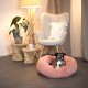 Ein kleiner Hund ruht sich in einem flauschigen rosa Haustierbett aus, umgeben von einem gemütlichen Wohnzimmer mit einem Stuhl, einer Pflanze und einer Lampe.