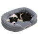 Ein schwarz-weißer Border Collie liegt bequem auf einem weichen, grauen Haustierbett mit einer plüschigen Oberfläche.