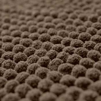 Nahaufnahme einer strukturierten braunen Haustierbettoberfläche mit kleinen, runden, plüschigen Erhebungen.