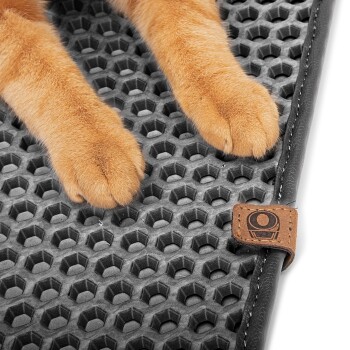 Nahaufnahme der Pfoten einer orangefarbenen Katze, die auf einer strukturierten schwarzen Matte mit Wabenmuster ruhen, mit einem kleinen braunen Etikett.