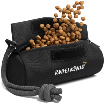 Eine schwarze Futterschüssel für Haustiere mit dem Text "RUDELKÖNIG" wird gezeigt, aus der Futterkibble aus der offenen Oberseite herausfällt.