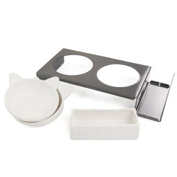 Ein Set von Fressnäpfen für Haustiere, bestehend aus zwei weißen Keramikschalen mit Katzenohren-Design und einem rechteckigen weißen Teller, platziert neben einem schwarzen Metallhalter.