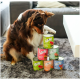 Ein brauner und weißer Hund untersucht neugierig einen Stapel bunter Dosen mit Haustierfutter, die mit "wow" beschriftet sind und Geschmäcker wie Rind mit Karotten und Wildlachs enthalten.