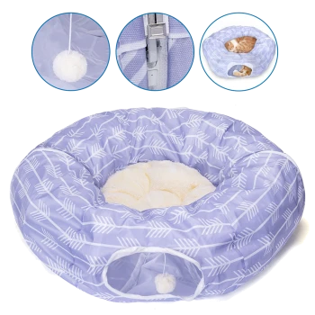 Ein gemütliches rundes Haustierbett in helllila mit weißen Pfeilmustern, mit einem plüschigen cremefarbenen Innenraum und einem hängenden Pom-Pom-Spielzeug.