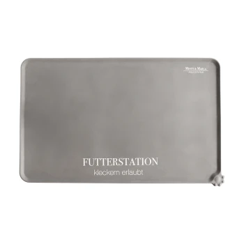 Graue Futtermatte für Haustiere mit dem Text "FUTTERSTATION" und "kleckern erlaubt" in Weiß gedruckt, mit abgerundeten Ecken und pfotenförmigen Griffen.