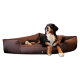 Ein Berner Sennenhund, der auf einem braunen Hundebett entspannt liegt, mit herausgestreckter Zunge und aufgerichteten Ohren.