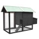 Ein graues Holzhaustierhaus mit grünem Dach, mit einem Netzfront, einer Eingangsrampe und einem seitlichen Stauraum.