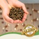 Hände halten einen Haufen dunkler, runder Tierfutterkibble, mit einem Abzeichen, das im Eck "Bewährte Qualität seit über 15 Jahren - Best Quality" besagt.