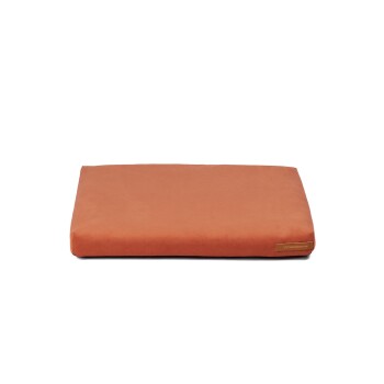 Ein rechteckiges Haustierbett in warmem Orange, mit einer glatten Oberfläche und einem kleinen Markenetikett in einer Ecke.